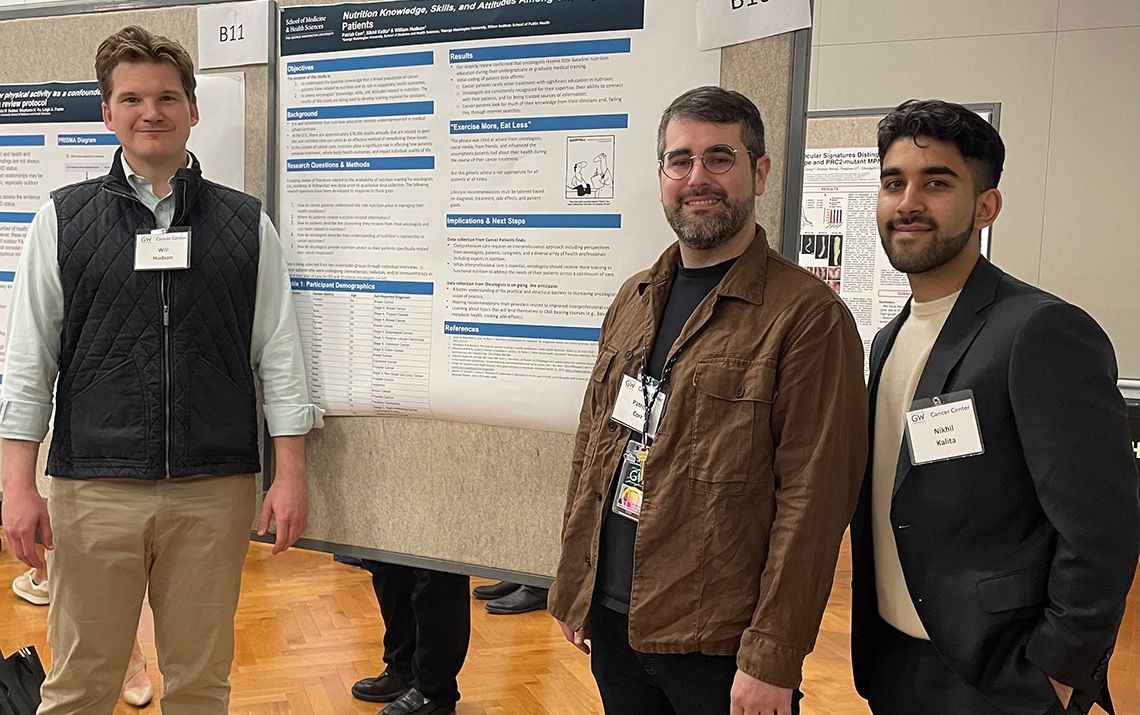 Three men stand in front of a research poster